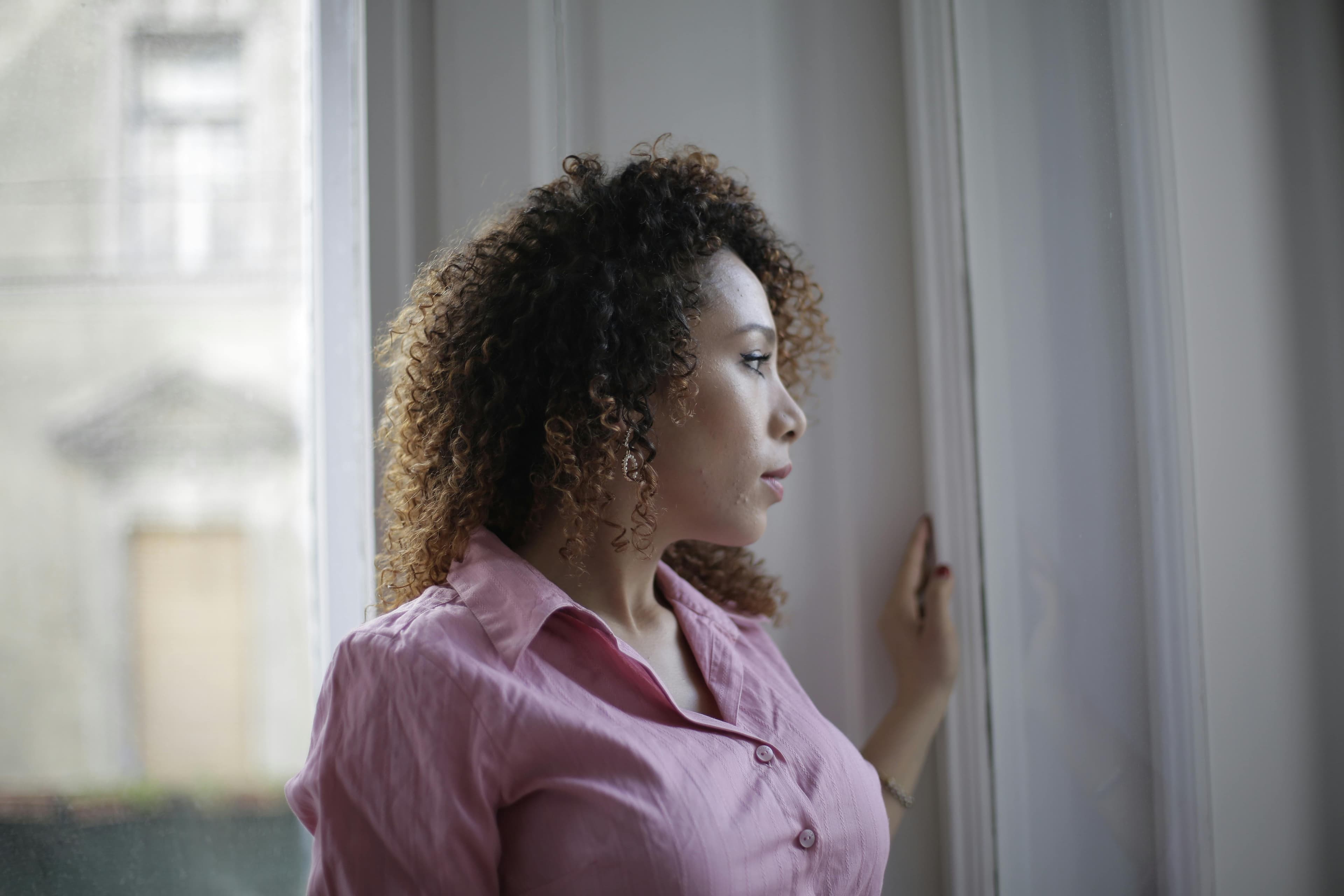 Latin woman with curly hair looking out the window Latin woman with curly hair looking out the window